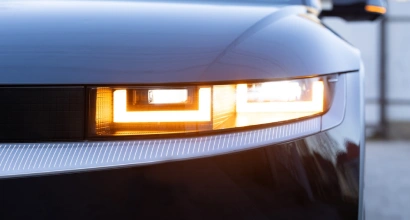 Close-up of a modern car’s LED headlight with amber turn signal illuminated, showcasing sleek and futuristic lighting design.