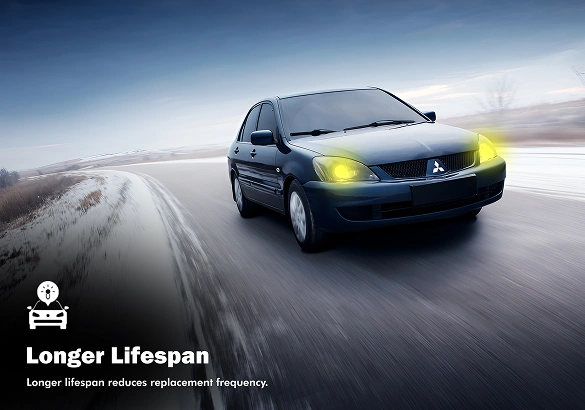 Black Mitsubishi sedan driving on a snowy road with glowing yellow headlights, accompanied by the text "Longer Lifespan – Longer lifespan reduces replacement frequency."