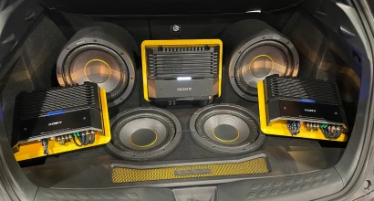 Custom car audio setup in a trunk featuring multiple Sony amplifiers and subwoofers with yellow mounting plates, arranged symmetrically for visual impact and high-performance sound.