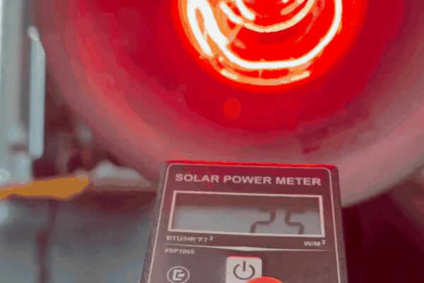 Animated gif showing a solar power meter held up to a red heat lamp, with the meter reading fluctuating as it detects radiant energy—used to demonstrate the heat-blocking effectiveness of window tint films.