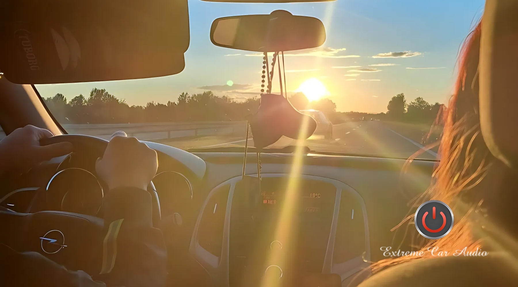 Interior view of a car driving into the sunset on a Louisiana highway, with golden sunlight pouring through the windshield and onto the driver's and passenger’s skin, visually emphasizing the need for UV protection. Captured in Marrero, LA, the image highlights how car windows can expose skin to intense sun, reinforcing the question: What Does Window Film Have to Do With Skin Care.