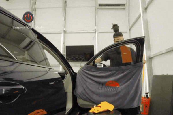 A technician at Extreme Car Audio LLC in Marrero, LA preps a car door for window tinting, using a Llumar-branded towel to protect the interior. The image supports the topic Choose Extreme Car Audio LLC for Your Tint by showcasing professional setup and branded materials that reflect quality service.
